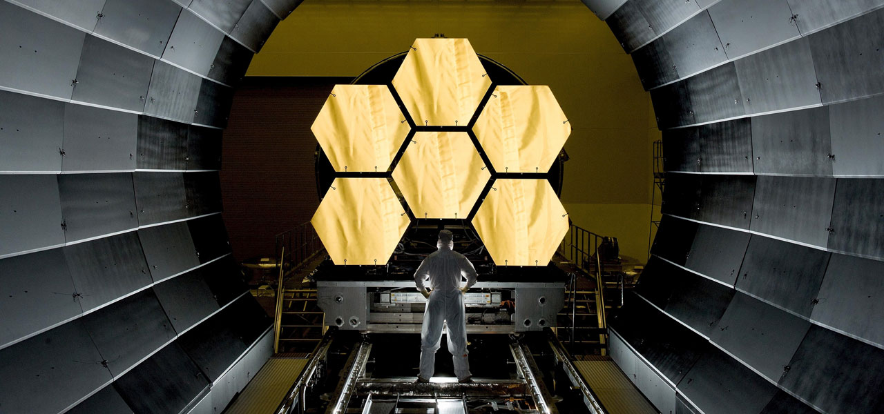 A man standing in front of mirror segments of the James Webb telescope.