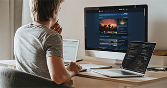 Hombre sentado frente a computadoras, mirando una página de la tienda Steam