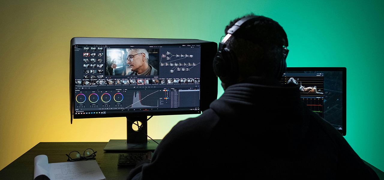 Un hombre sentado frente a una computadora, editando un video